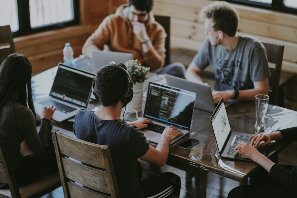 Team arbeitet gemeinsam mit Laptops an einem Tisch und entwickelt Ideen